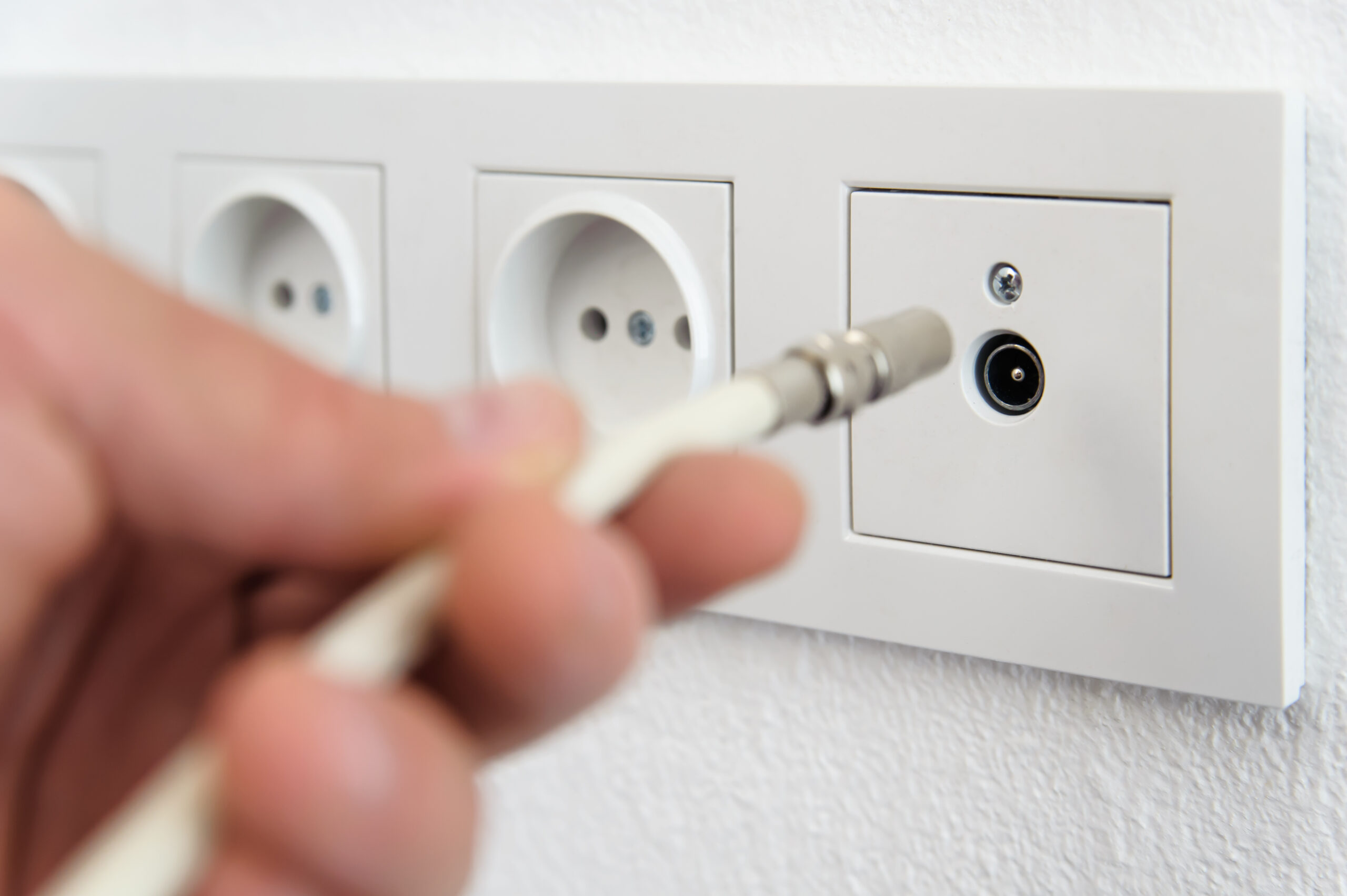 Human hand inserts the antenna cable to the TV outlet