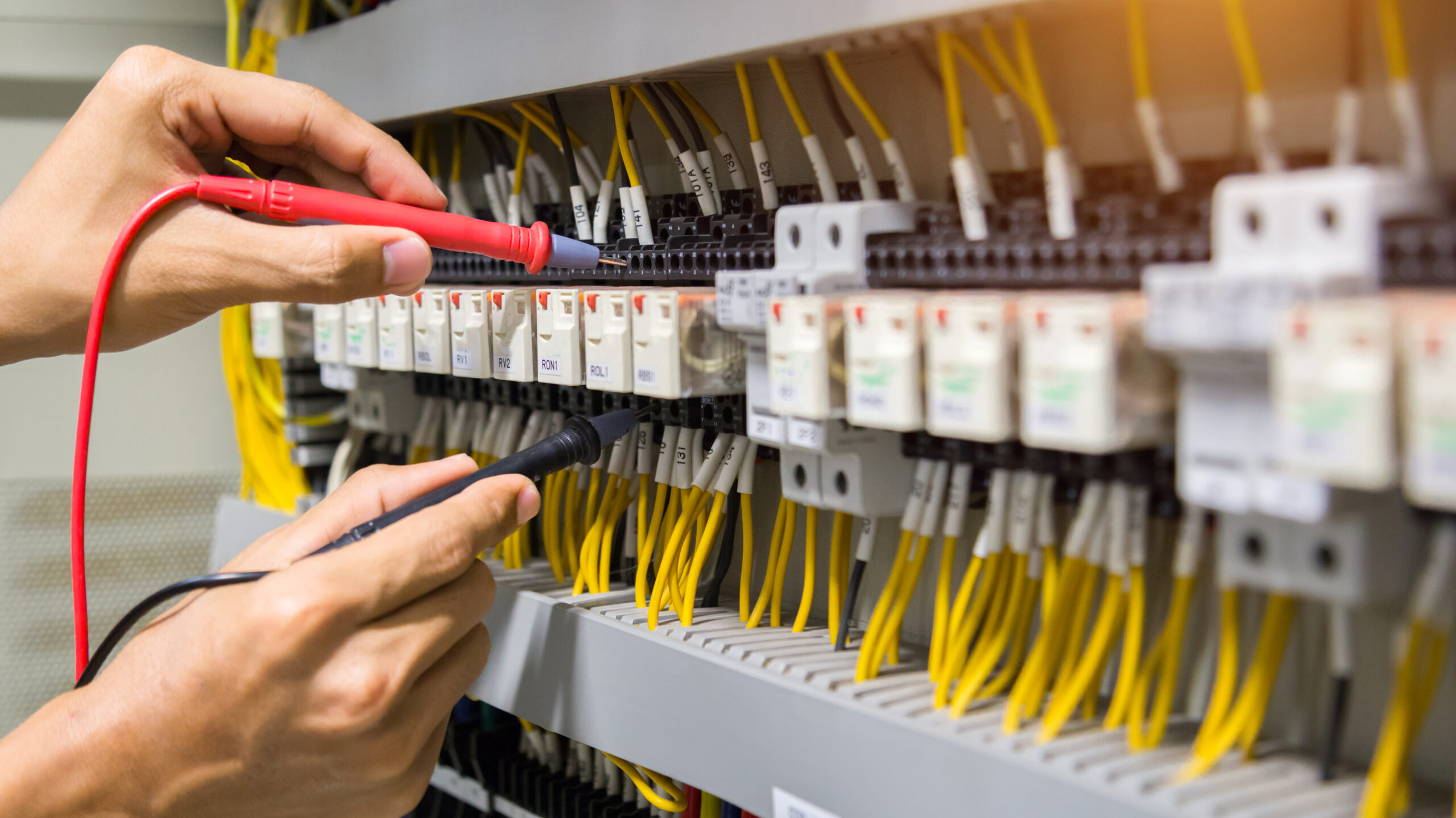 Electricians hands testing current  electric in control panel.
